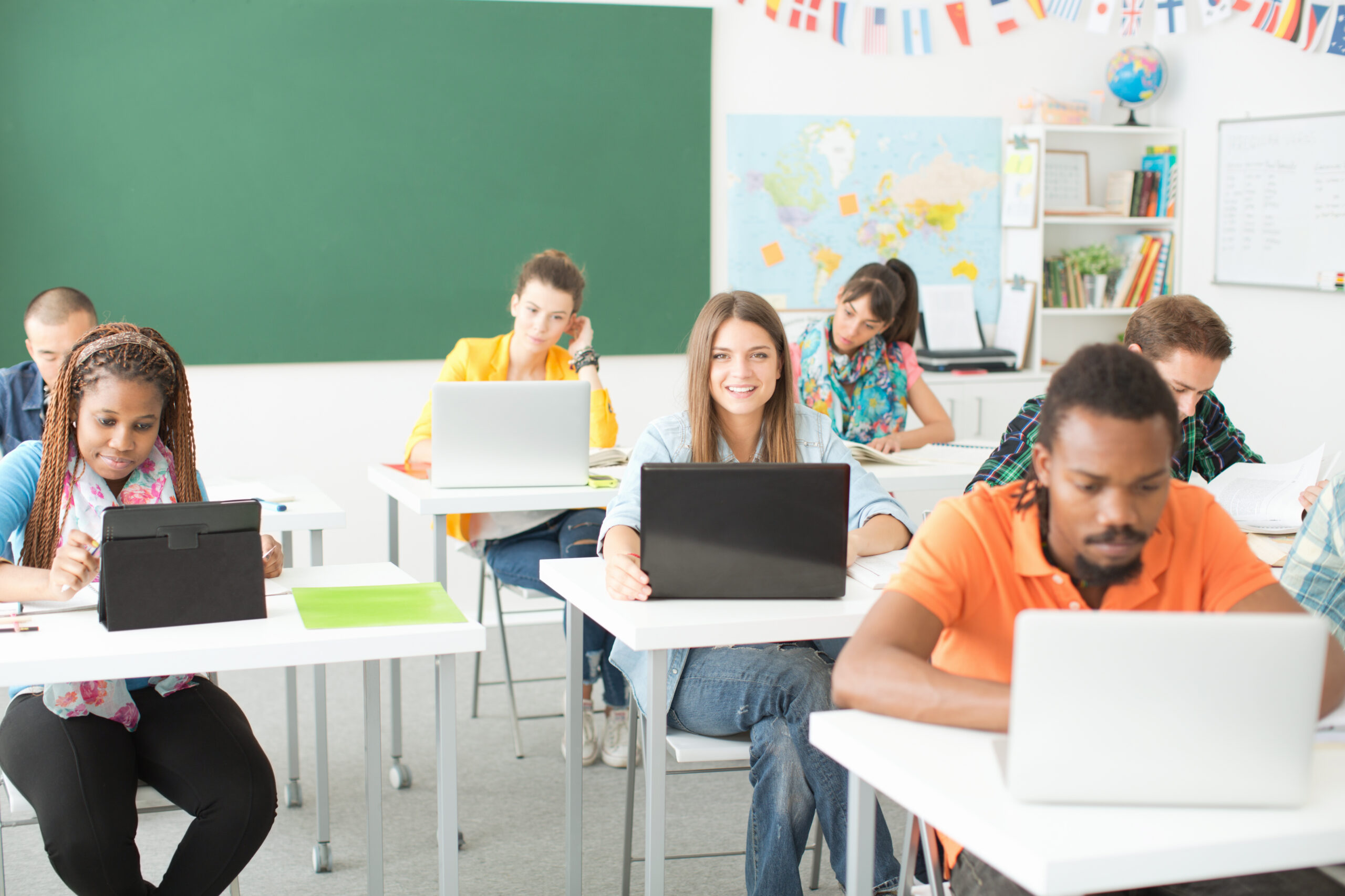 Schlüer sitzen im Klassenzimmer und arbeiten an ihren Laptops.